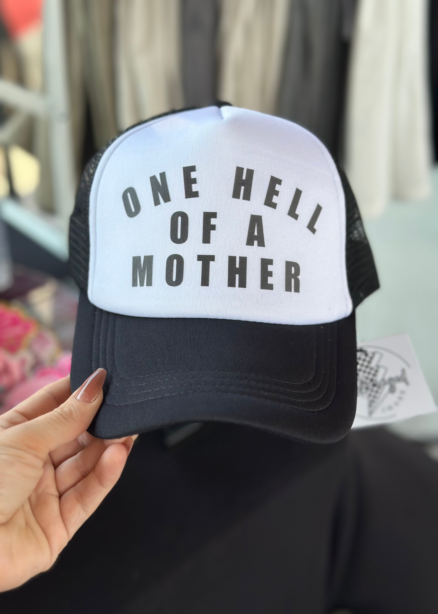 Black trucker hat with white foam front panel - Black text reading "One Hell of a Mother"